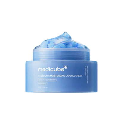 Geöffneter Tiegel der Medicube Hyaluronic Moisturizing Capsule Cream mit blauen Kapseln und transparentem Gel auf weißem Hintergrund
