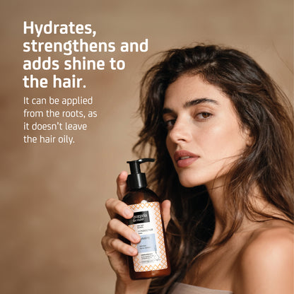Frau hält den Nuggela & Sulé Hydrating Conditioner neben ihr Haar